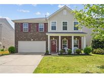 Charming two-story home featuring a brick facade, inviting front porch, and a well-maintained lawn at 6041 Laurent Ave, Fort Mill, SC 29715