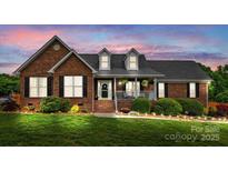Charming brick home with manicured lawn, dormers, and inviting front porch with decorative shrubbery at 6713 Edwards Farm Ln, Monroe, NC 28110