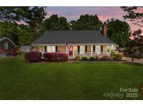 Charming single-story home with a well-manicured lawn, covered porch, and traditional American flag at 806 Mcgregor Ne Dr, Concord, NC 28025