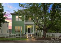 Inviting two-story home with a spacious porch and balcony, framed by lush greenery and a twilight sky at 136 Water Oak Dr, Mooresville, NC 28117