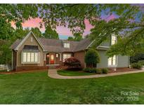 Charming home with well-manicured lawn and orange door, framed by a beautiful, colorful sky at 174 Buffalo Creek Dr, Statesville, NC 28677