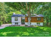 Stunning updated split level home boasts a striking facade with modern siding, black trim windows, and lush landscaping at 200 Kimrod Ln, Charlotte, NC 28270