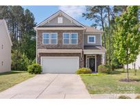 Charming two-story home with stone accents, attached garage and well-manicured lawn at 2214 Laurens Dr, Concord, NC 28027