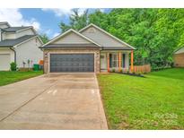 Charming single-story home features a dark garage door and brick accents at 7328 Starvalley Dr, Charlotte, NC 28210