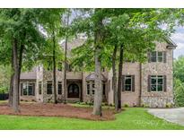 Stately stone and brick home featuring multiple windows, a lush front lawn and mature shade trees at 925 Giacomo Dr, Waxhaw, NC 28173