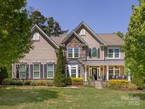 Beautiful two-story home with a stone facade, covered porch, manicured lawn, and mature trees at 10716 Meg Meadow Dr, Mint Hill, NC 28227