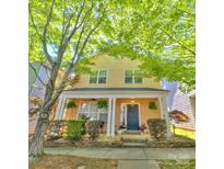 Charming yellow two-story home with a inviting front porch and lush landscaping at 240 Faust Rd, Davidson, NC 28036