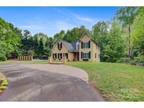 Charming two-story home featuring manicured lawn, circular driveway, and mature trees at 3125 Arden Way, Claremont, NC 28610