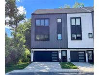 Modern townhome with a sleek gray and white exterior and black garage doors at 3538 Saker Ln, Charlotte, NC 28211