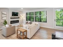 Bright living room with a modern fireplace and large windows offering natural light and outdoor views at 3538 Saker Ln, Charlotte, NC 28211