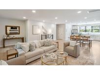 Bright open-concept living room with a light sofa, modern decor, and hardwood floors at 3538 Saker Ln, Charlotte, NC 28211
