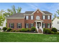Charming two-story red brick home with black shutters, manicured lawn, and inviting front porch at 4015 Amber Leigh Way Dr, Charlotte, NC 28269