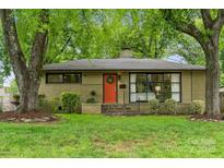 Charming ranch-style home with an orange front door, landscaped yard, mature trees, and black framed windows at 513 Inwood Dr, Charlotte, NC 28209