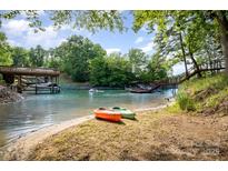 Scenic waterfront view with kayaks on the beach, docks, a boat, and lush trees under a sunny blue sky at 9066 Tulagi Ct, Tega Cay, SC 29708