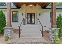 Inviting front entrance with black double doors, wooden pillars, painted brick, and stone accents create a modern aesthetic at 1118 Crestbrook Dr, Charlotte, NC 28211