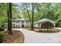 Charming traditional home with a circular driveway, lush landscaping, and mature trees at 6868 St Peters Ln, Matthews, NC 28105