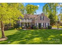 Stately brick home featuring a manicured lawn and covered front porch with white pillars and railing at 7896 Harbor Master Ct, Denver, NC 28037