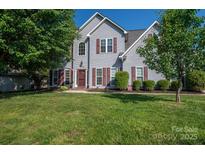 Charming two-story home with well-maintained lawn, mature trees, and classic architectural details at 7905 Sedgebrook E Dr, Stanley, NC 28164