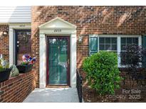 Inviting brick townhome entrance features a classic door with decorative trim and a well-maintained landscape at 8835 Hunter Ridge Dr, Charlotte, NC 28226