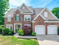Traditional brick home featuring a two-car garage, manicured lawn, and mature landscaping at 1103 Cooper Ln, Indian Trail, NC 28079
