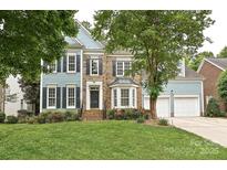 Charming two-story home with blue siding, brick accents, black shutters, a well-manicured lawn, and mature trees at 11232 Tradition View Dr, Charlotte, NC 28269