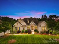 Beautiful brick home featuring manicured landscaping and mature trees at dusk at 1128 Rosecliff Dr, Marvin, NC 28173