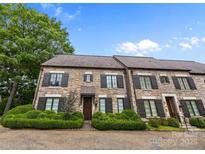 Charming stone townhome featuring a well-manicured front yard with lush green hedges and dark shutters at 1550 High St, Charlotte, NC 28211