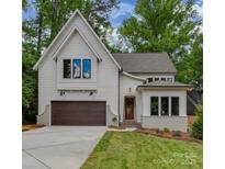 Charming two-story home featuring a gabled roof, wood garage door, and nicely landscaped front yard at 1807 Arnold Dr, Charlotte, NC 28205