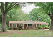 Charming brick home with covered porch and carport, surrounded by lush trees and landscaping at 2412 Wedgewood Dr, Salisbury, NC 28146