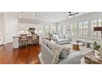 Bright, open-concept living space featuring hardwood floors, and white cabinets with granite countertops at 329 Brambling Ct, Wesley Chapel, NC 28110