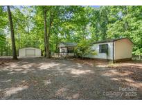 Charming home exterior with a welcoming front porch and storage shed nestled in a wooded lot at 351 Fletcher Rd, Union Grove, NC 28689