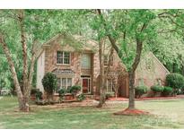Charming two-story brick home featuring a landscaped front yard, mature trees and shuttered windows at 4410 Laurel Twig Ct, Charlotte, NC 28215