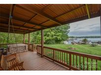 Covered porch with a porch swing, hot tub and beautiful views of the landscaped yard and lake at 7942 Vista View Dr, Sherrills Ford, NC 28673