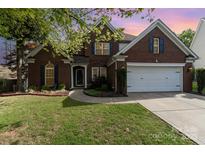 Charming brick two-story home featuring a well-manicured lawn, landscaping, and two car garage at 13406 Ada Ct, Charlotte, NC 28213