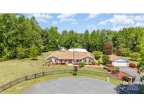 Beautifully landscaped brick ranch home with manicured lawn, circular drive, and a backdrop of mature trees at 14834 Pawnee Trl, Matthews, NC 28104