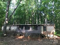 Mobile home with a covered porch surrounded by a wooded landscape at 163 Shanna Ln, Statesville, NC 28625