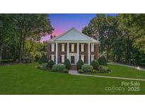 Stately brick home with white columns, black shutters, manicured lawn, and mature trees at 1721 White Pond Ln, Waxhaw, NC 28173