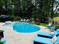 Beautiful backyard pool area with ample seating, lounge chairs and mature trees at 19409 Laurel Glen Ave, Cornelius, NC 28031