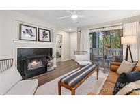 Cozy living room with fireplace, ceiling fan, hardwood floors, and a sliding glass door to the balcony at 611 Olmsted Park Pl # C, Charlotte, NC 28203
