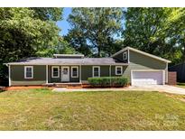 Charming single-story home with green siding, a well-manicured lawn, and an attached garage at 619 Archibald Rd, Concord, NC 28025