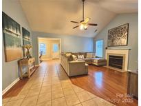 Spacious living room featuring a fireplace, ceiling fan, and hardwood flooring transitioning to tile near the dining area at 10408 Milstead Ct, Charlotte, NC 28215