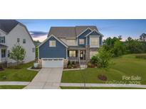 Charming two-story home featuring a stone facade, covered porch, and well-manicured lawn at 14218 Morningate St, Huntersville, NC 28078