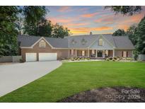 Charming brick home features a manicured lawn, mature trees, and an attached two-car garage at 17112 Green Dolphin Ln, Cornelius, NC 28031