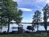 Picturesque waterfront view featuring a private dock and boat, surrounded by lush greenery and serene water at 17112 Green Dolphin Ln, Cornelius, NC 28031