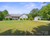 Charming single-story home with a lush lawn, complemented by a detached two-car garage and a tree-lined landscape at 260 Treebark Rd, Statesville, NC 28625