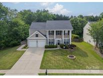Traditional two-story home featuring a two-car garage, well-maintained lawn, and mature trees at 8707 Darcy Hopkins Dr, Charlotte, NC 28277