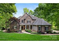 Beautiful two story home with a brick facade, manicured lawn, mature trees, and charming walkway at 9013 Yellow Pine Ct, Waxhaw, NC 28173