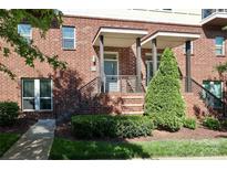 Inviting brick townhome entrance with manicured landscaping, covered entryway, and iron railings at 926 Steel House Blvd, Charlotte, NC 28205