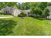 Charming single-story home with an attached garage, lush lawn, and mature landscaping at 11224 Amber Glen Dr, Charlotte, NC 28269