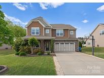 Two story home featuring a stone and tan facade, manicured landscaping and a two car garage at 137 Sugar Magnolia Dr, Mooresville, NC 28115